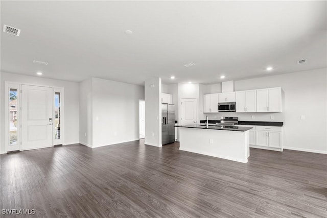 kitchen with a kitchen island with sink, dark wood-type flooring, stainless steel appliances, and white cabinetry