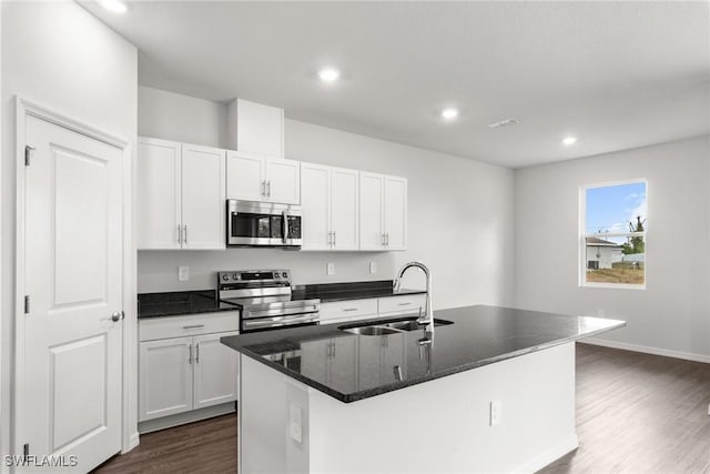 kitchen with white cabinets, a kitchen island with sink, appliances with stainless steel finishes, and sink