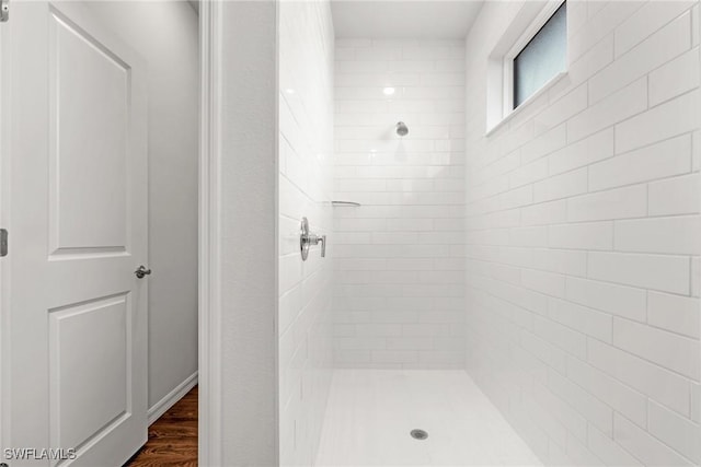 bathroom featuring wood-type flooring and a tile shower