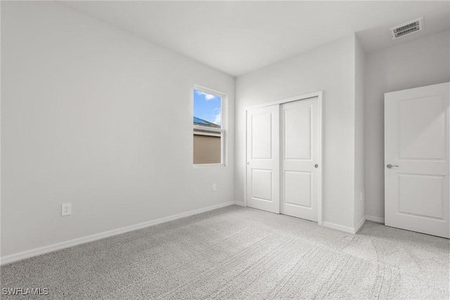 unfurnished bedroom featuring a closet and light colored carpet