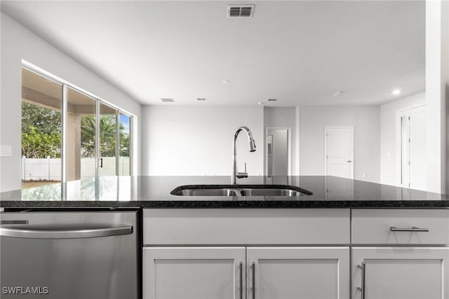 kitchen featuring dishwasher, white cabinets, dark stone counters, and sink