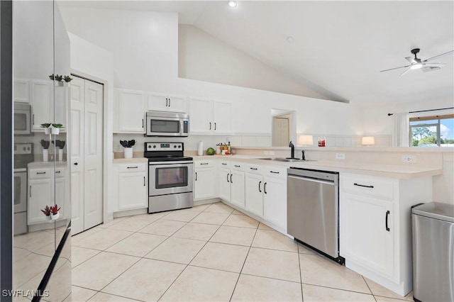 kitchen featuring light tile patterned floors, sink, stainless steel appliances, white cabinets, and kitchen peninsula