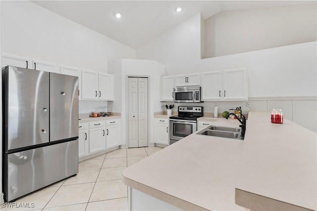 kitchen featuring appliances with stainless steel finishes, high vaulted ceiling, white cabinetry, sink, and kitchen peninsula