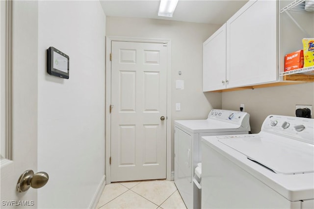 laundry area with cabinets, separate washer and dryer, and light tile patterned floors