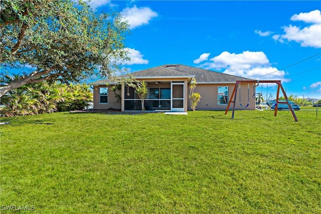 rear view of property featuring a lawn, a sunroom, and a playground