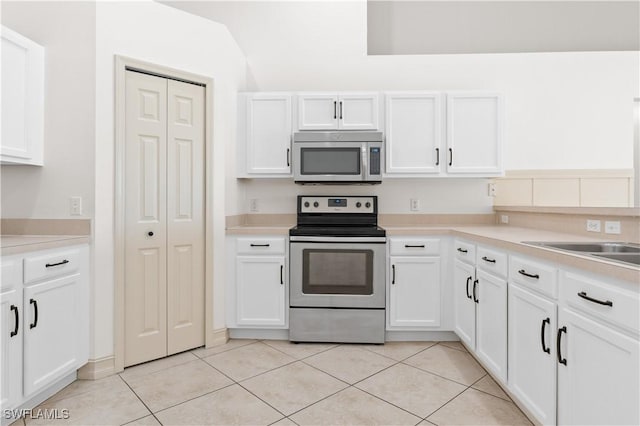 kitchen featuring stainless steel appliances, light tile patterned floors, and white cabinets