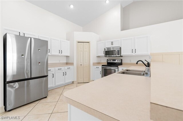 kitchen with light tile patterned flooring, sink, white cabinetry, high vaulted ceiling, and stainless steel appliances