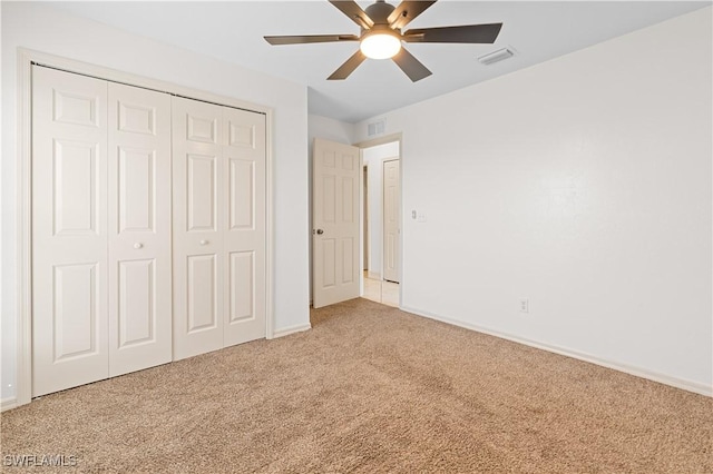 unfurnished bedroom with ceiling fan, light colored carpet, and a closet