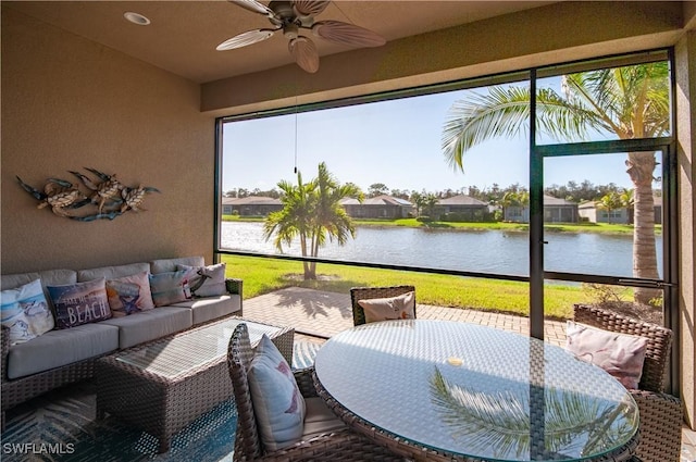 sunroom featuring a water view and ceiling fan