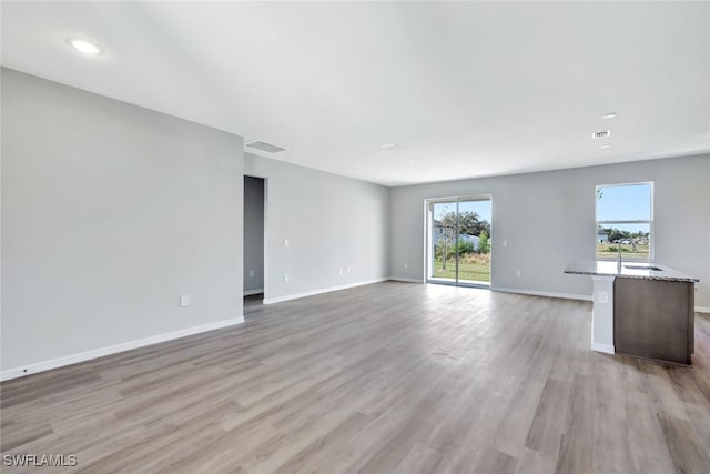 unfurnished living room with light hardwood / wood-style floors and sink