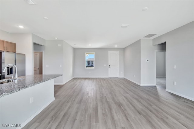 unfurnished living room with light wood-type flooring and sink