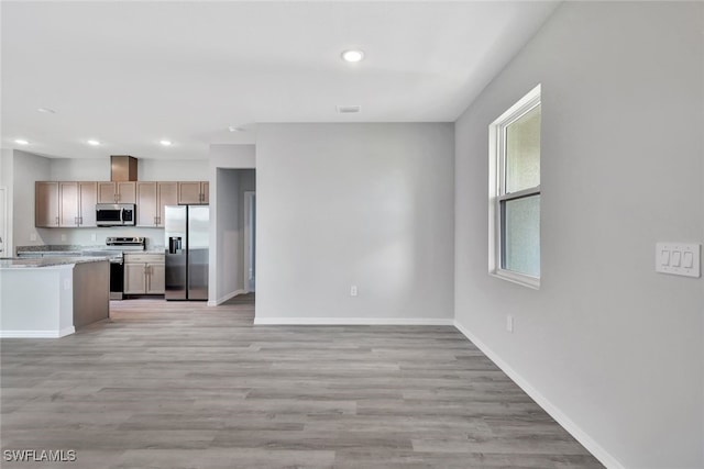 kitchen with light stone counters, light brown cabinetry, light hardwood / wood-style flooring, and appliances with stainless steel finishes