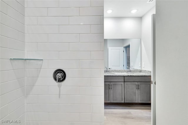 bathroom with a tile shower, vanity, and hardwood / wood-style flooring