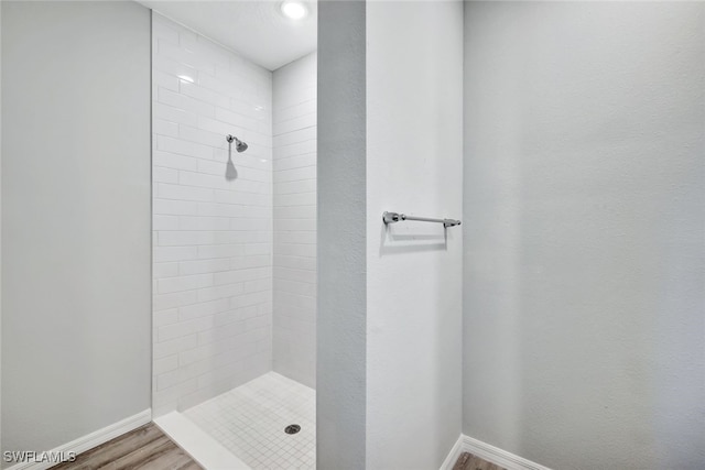 bathroom with a tile shower and wood-type flooring