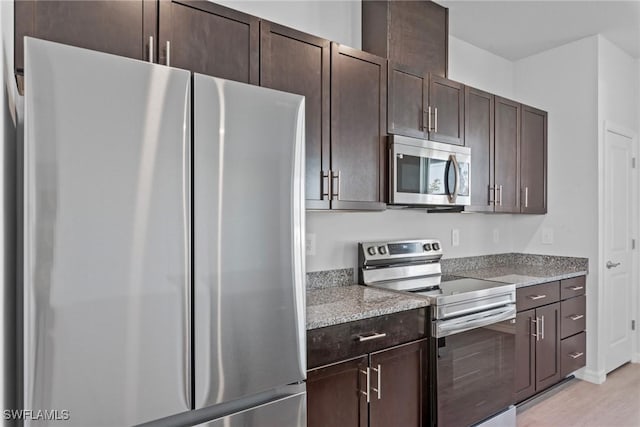 kitchen featuring light stone countertops, dark brown cabinets, and appliances with stainless steel finishes