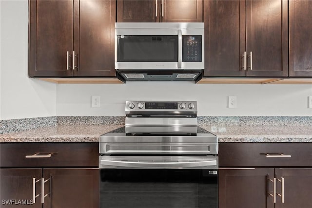 kitchen featuring light stone counters, dark brown cabinetry, and stainless steel appliances