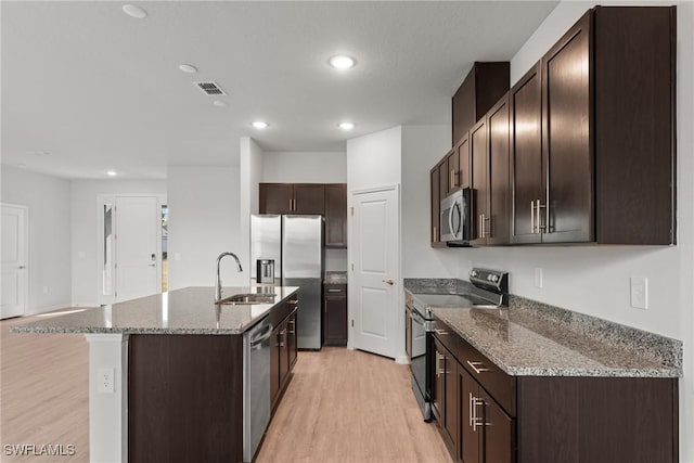 kitchen with stainless steel appliances, light hardwood / wood-style flooring, a kitchen island with sink, and sink