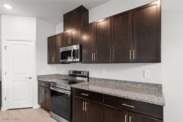 kitchen with dark brown cabinets, light stone countertops, and appliances with stainless steel finishes