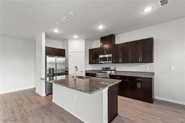 kitchen featuring stainless steel appliances, a kitchen island with sink, light hardwood / wood-style floors, and sink