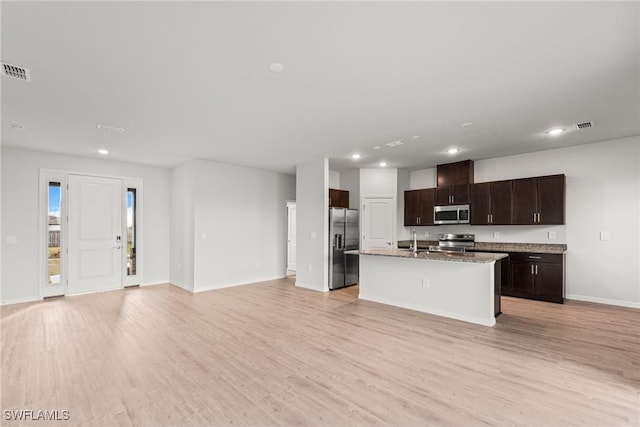 kitchen with a kitchen island with sink, sink, light wood-type flooring, appliances with stainless steel finishes, and dark brown cabinetry