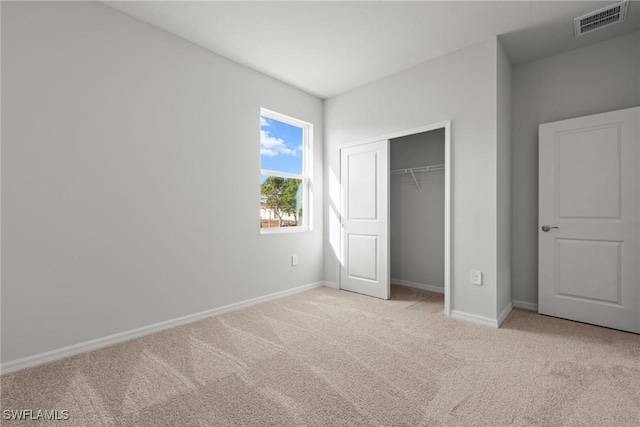 unfurnished bedroom with light colored carpet and a closet