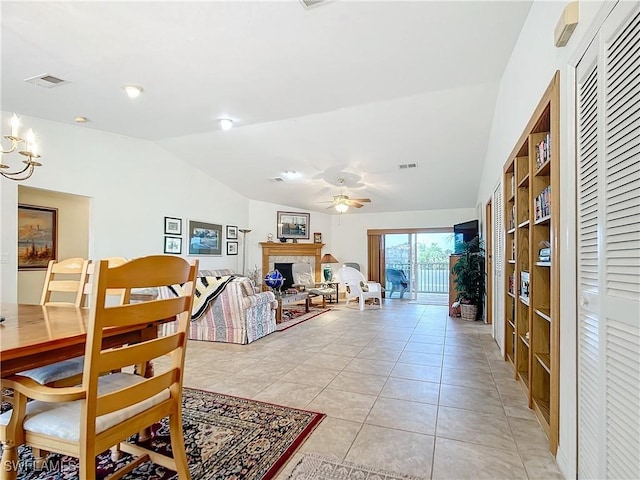 tiled dining space featuring ceiling fan with notable chandelier and lofted ceiling