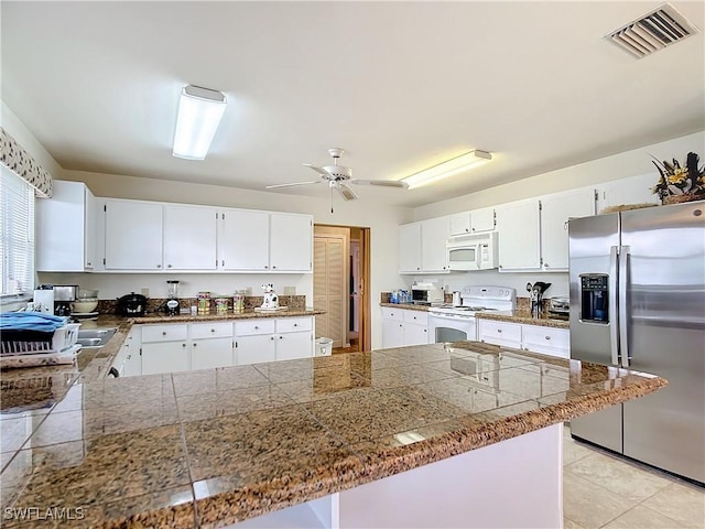 7397 Grande Pine Rd, Bokeelia, FL 33922 - kitchen with ceiling fan, light tile patterned flooring, kitchen peninsula, white appliances, and white cabinets