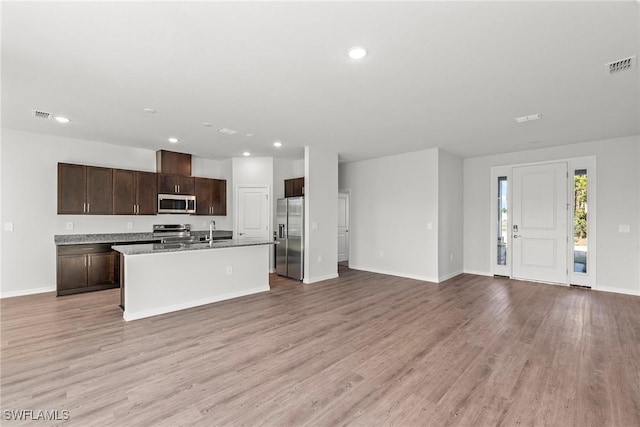 kitchen featuring sink, light hardwood / wood-style floors, a kitchen island with sink, dark brown cabinets, and appliances with stainless steel finishes