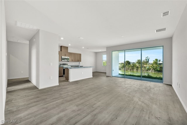 unfurnished living room with light hardwood / wood-style floors and a healthy amount of sunlight