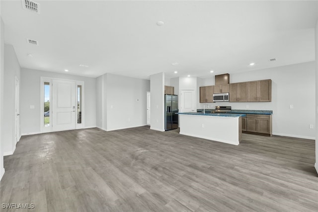 kitchen with stainless steel appliances, a kitchen island with sink, light hardwood / wood-style floors, and sink