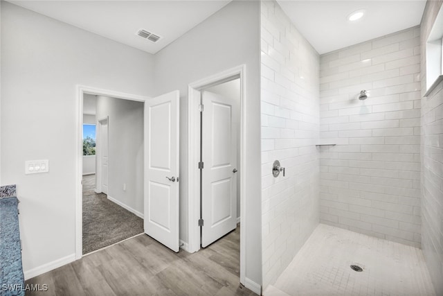 bathroom with a tile shower and hardwood / wood-style floors