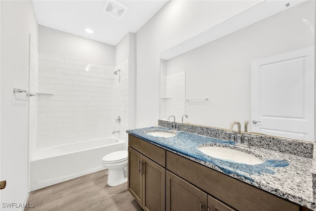 full bathroom with hardwood / wood-style floors, vanity, shower / bath combination, and toilet