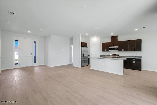 kitchen with sink, an island with sink, light wood-type flooring, and appliances with stainless steel finishes