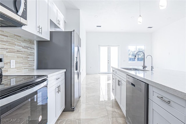 kitchen featuring a sink, marble finish floor, stainless steel appliances, white cabinetry, and backsplash