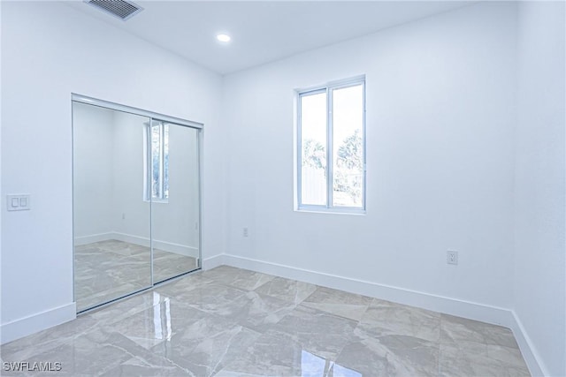 unfurnished bedroom with marble finish floor, baseboards, visible vents, and a closet