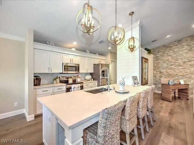 kitchen featuring white cabinetry, a kitchen breakfast bar, a notable chandelier, decorative light fixtures, and appliances with stainless steel finishes