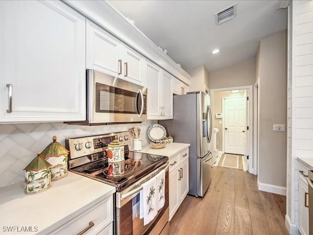 kitchen featuring white cabinets, stainless steel appliances, light hardwood / wood-style flooring, and lofted ceiling