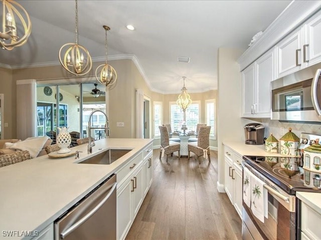 kitchen with hanging light fixtures, white cabinetry, sink, and appliances with stainless steel finishes