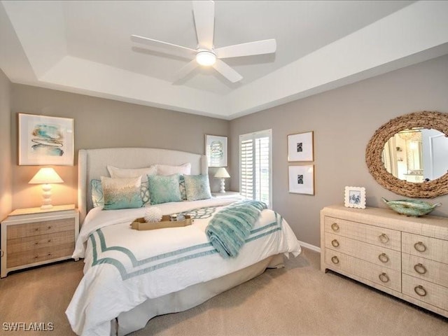 carpeted bedroom with a tray ceiling and ceiling fan