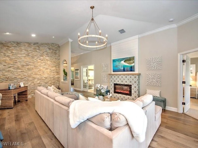 living room featuring crown molding, lofted ceiling, a fireplace, and a chandelier