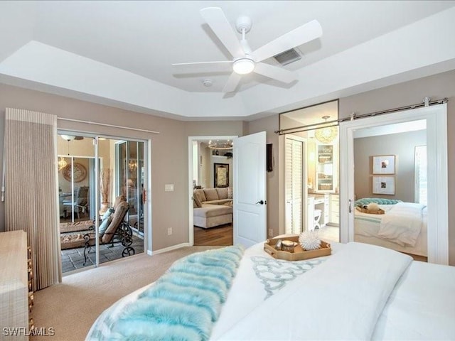 bedroom featuring access to outside, a tray ceiling, ceiling fan, and light colored carpet