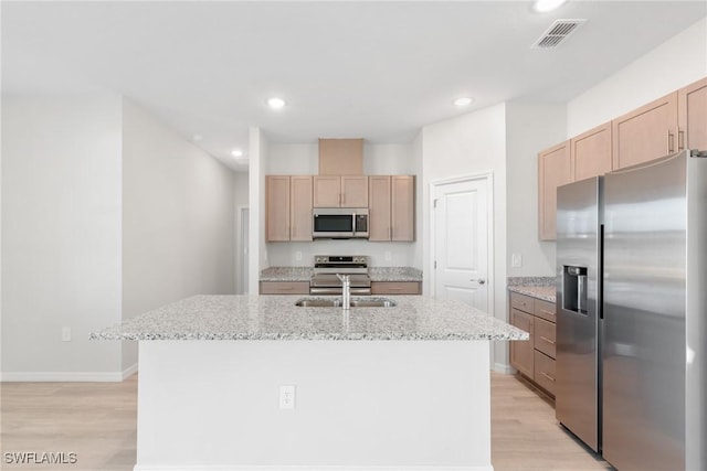 kitchen featuring light stone countertops, stainless steel appliances, sink, a center island with sink, and light hardwood / wood-style flooring