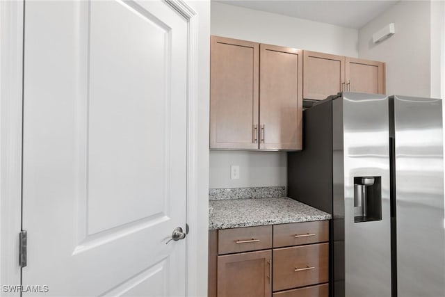 kitchen with light stone countertops and stainless steel fridge with ice dispenser