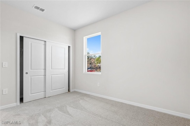 unfurnished bedroom with a closet and light colored carpet