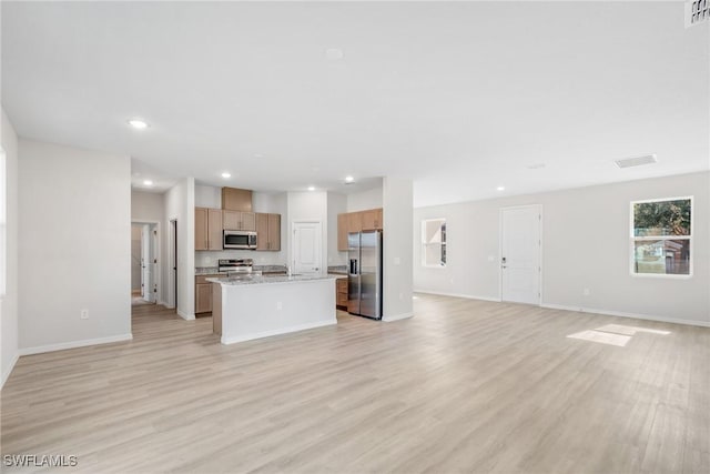 kitchen featuring a center island, light wood-type flooring, light stone countertops, and stainless steel appliances