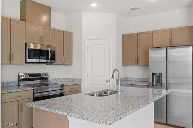 kitchen featuring light stone counters, sink, an island with sink, and stainless steel appliances