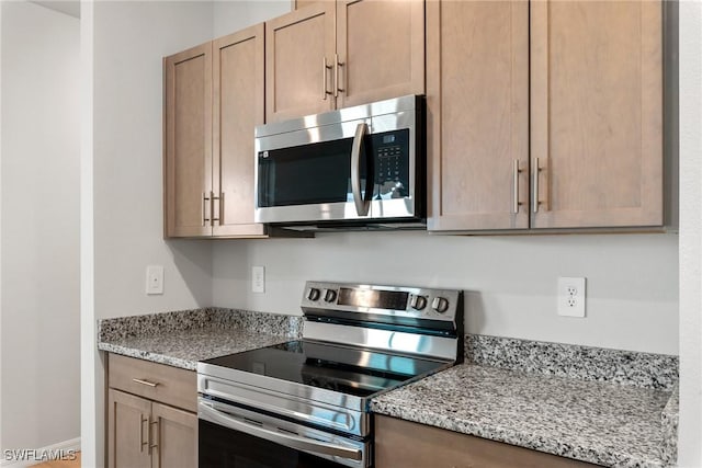 kitchen with light stone counters, light brown cabinetry, and appliances with stainless steel finishes