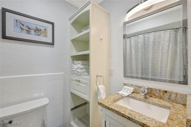 bathroom featuring vanity, toilet, and tile walls