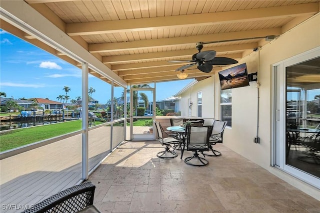 sunroom with beam ceiling, ceiling fan, and a water view