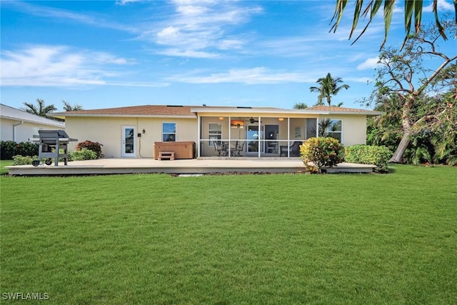 back of house with a sunroom, a lawn, a wooden deck, and a hot tub